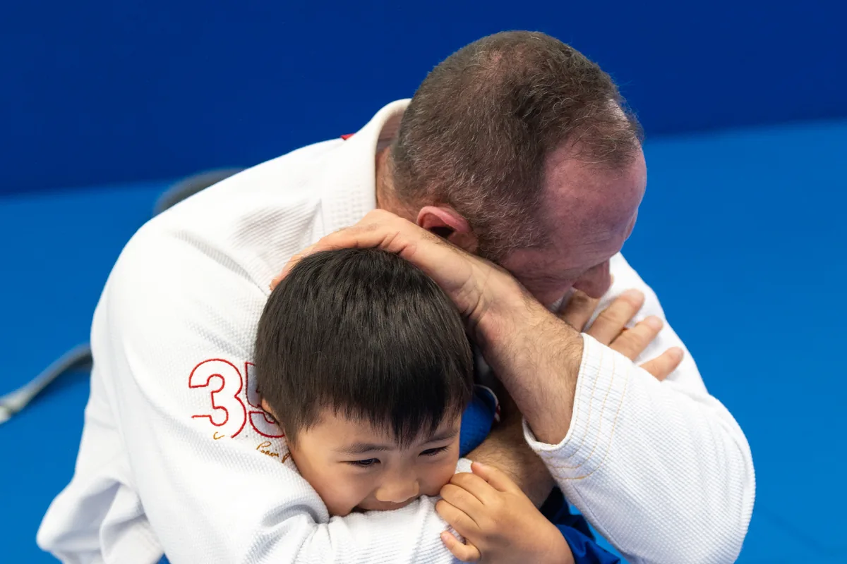 A coach helping a child practise Jiu-Jitsu